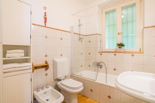a white bathroom with a toilet and a sink at Two floors APT with shared pool and parking! in Villa Guardia