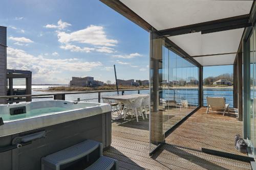 Una bañera en una terraza con vista al agua. en Villa Super VIP - 4 Pers met jacuzzi - Villa 7, en Ouddorp