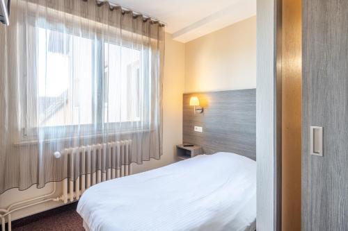 a small bedroom with a bed and a window at Hôtel Restaurant Oberlé in Kilstett