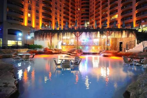 a building with tables and chairs and a fountain at night at Goldctiy otel villa in Alanya