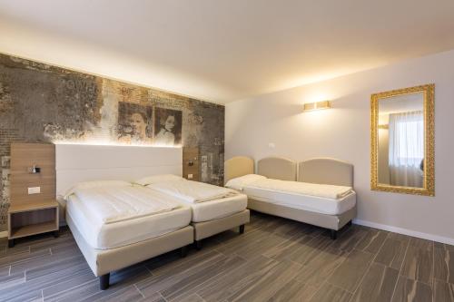 a bedroom with two beds and a mirror at Pace 1954 Hotel in Arco