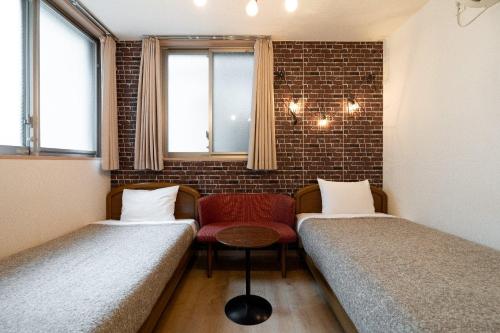 een kamer met 2 bedden en een rode stoel bij City Oasis in Tokyo