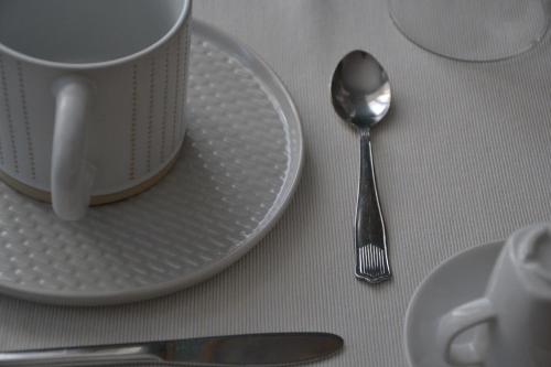 a white plate with a coffee cup and a spoon at B&B Mirabelle in Pinerolo