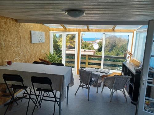 une salle à manger avec une table et des chaises et une fenêtre dans l'établissement Mobil-home vue océan/400 m de la plage à Saint Jean de Luz, à Saint-Jean-de-Luz