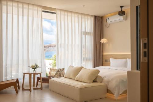 a bedroom with a bed and a couch and a window at Dali Qiyu Half Hill Seaview Villa - Erhai Branch in Dali