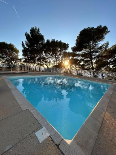 une piscine bleue avec des arbres en arrière-plan dans l'établissement Magnifique T2 Athena, à Bandol
