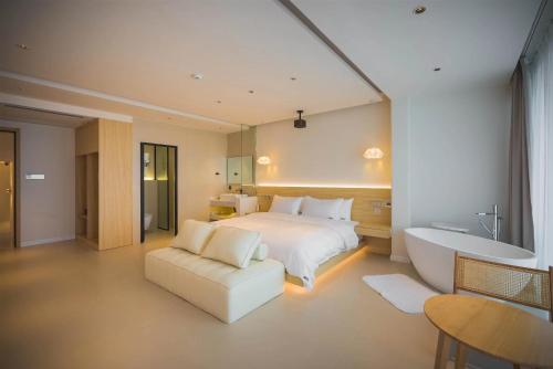 a bedroom with a bed and a bathtub and a white bed at Dali Qiyu Half Hill Seaview Villa - Erhai Branch in Dali