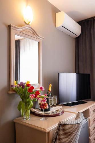 a desk with a television and a vase of flowers on it at Hotel Brilliant Meseș in Zalău