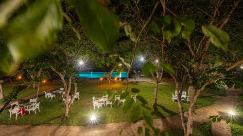 a lawn with white tables and chairs at night at Kassapa Lions Rock in Sigiriya
