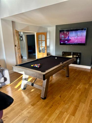 a pool table in a living room with a tv at Serene Retreat - Hot Tub - Pool Table - Close to New Forest and Bournemouth Beach - Sleeps 12 in Hurn