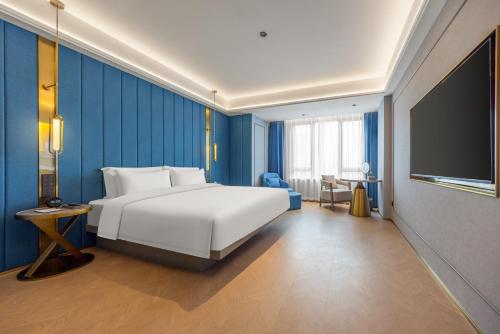 南寧市にあるMido Hotel - Nanning Anji Wanda Plaza Branchのベッドと薄型テレビがあるホテルの部屋