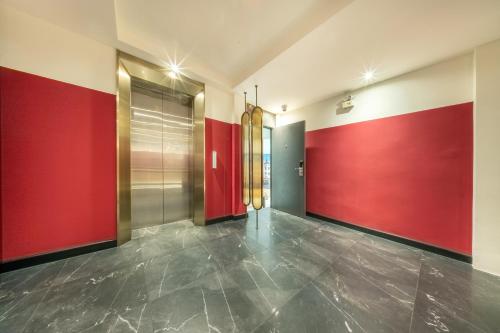 a hallway with red walls and a metal elevator at U TOR Yaowarat in Bangkok