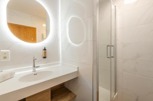 a white bathroom with a sink and a shower at Hôtel Restaurant Oberlé in Kilstett