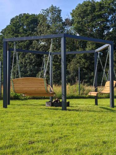 two swings in a park with green grass at Domki RELAXO Rewal in Rewal