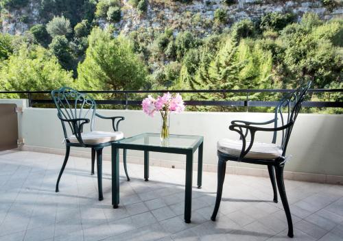 two chairs and a table with a vase of flowers on a balcony at Hilton Sorrento Palace in Sorrento