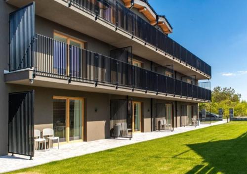 a building with chairs and a lawn in front of it at Lake-Apart Apartamenty Mielno in Mielno
