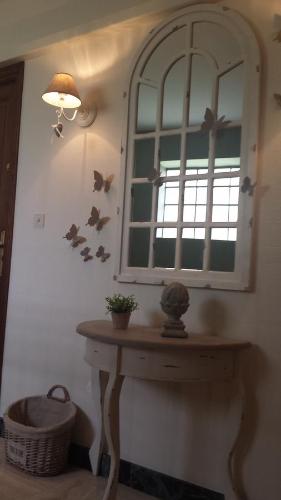 Habitación con espejo y mesa con pájaros en la pared. en Appartement De La Vallée, en Saint-Martin-le-Beau