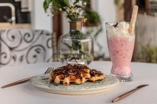a plate of food on a table next to a pink drink at Hotel Boutique Patio del Posadero in Córdoba