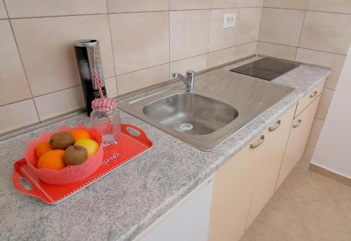 杜布罗夫尼克Apartman Luka的厨房柜台设有水槽和一碗水果