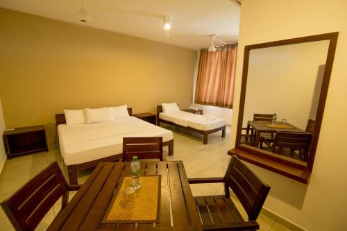a hotel room with a bed and a table and a mirror at SERENITY REST by Colombo YMBA in Kataragama