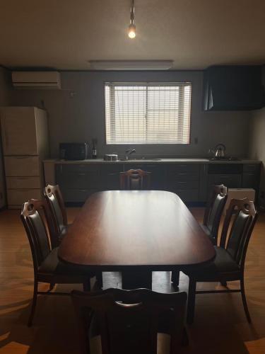 a kitchen with a wooden table and chairs and a table and a kitchen at suzume in Imabari