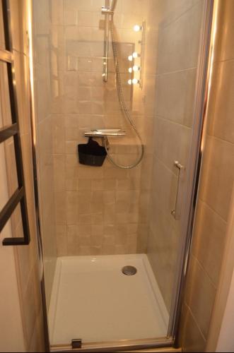 une douche avec une porte vitrée dans une salle de bain dans l'établissement Blue Cottage, à Plérin