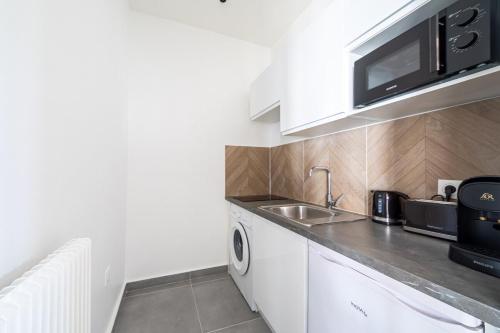 une cuisine avec un évier et un micro-ondes dans l'établissement Studio coloré Entre Versailleset Paris- III, à Issy-les-Moulineaux