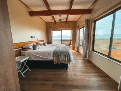 a bedroom with a bed and large windows at Pongola Poort Safari Camp in Bethel
