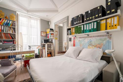 - une chambre avec un grand lit blanc et des étagères dans l'établissement Veeve - Playful Atelier, à Paris