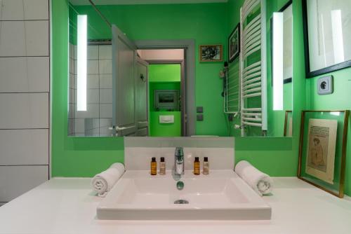 La salle de bains verte est pourvue d'un lavabo et d'un miroir. dans l'établissement Veeve - Playful Atelier, à Paris