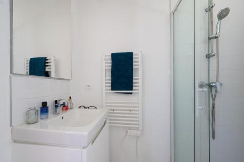 a white bathroom with a sink and a shower at Résidence Néméa Les Carrats - Port Leucate in Port Leucate