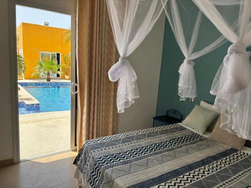 a bedroom with a bed with a view of a pool at Hôtel Colibri Lac Rose in Niaga