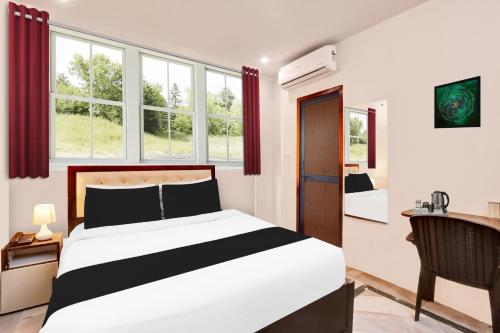 a bedroom with a bed and a desk and windows at Super Hotel O MVP Double Road in Visakhapatnam