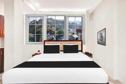 a bedroom with a black and white bed and windows at Super Hotel O MVP Double Road in Visakhapatnam