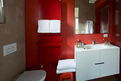 a red tiled bathroom with a sink and a toilet at Milan Design Suites 3 ROOMS in Milan