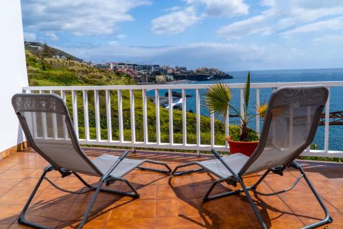 zwei Stühle auf einem Balkon mit Blick auf den Ozean in der Unterkunft Villa Irene in Funchal