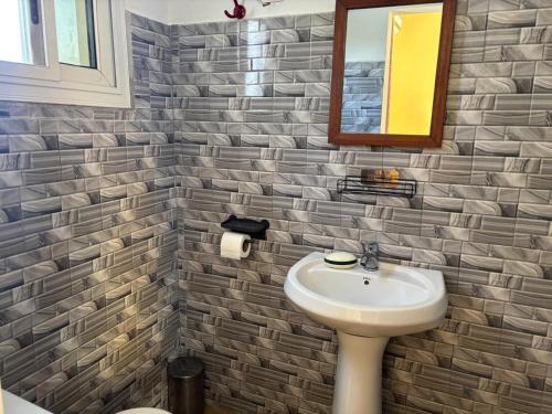 a bathroom with a sink and a mirror at Hôtel Colibri Lac Rose in Niaga