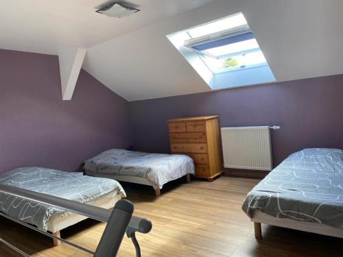 une chambre mansardée avec deux lits et une lucarne dans l'établissement Maison charmante à Munwiller avec terrasse et parking gratuit., à Munwiller