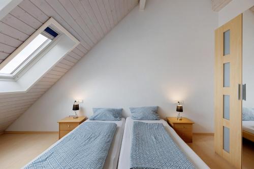 a attic bedroom with two beds and a window at Obstbau Koch in Bodman-Ludwigshafen