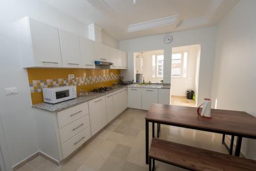 a kitchen with white cabinets and a wooden table at Flamingo Apartment 4 in Fouchana