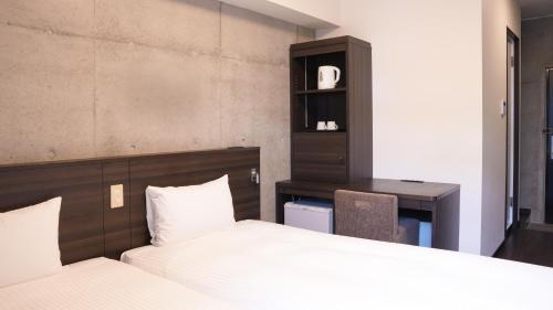 a bedroom with a bed and a desk and a chair at The BREAKFAST HOTEL PORTO Ishigakijima in Ishigaki Island