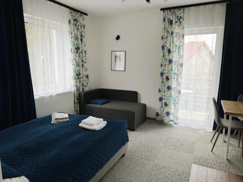 a bedroom with a bed and a couch and a window at Apartamenty Wczasowa - z widokiem na góry, parkingiem, rowerownią in Kudowa-Zdrój