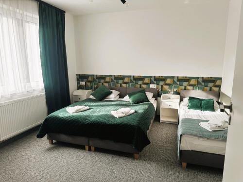 a hotel room with two beds and a bed and a window at Apartamenty Wczasowa - z widokiem na góry, parkingiem, rowerownią in Kudowa-Zdrój