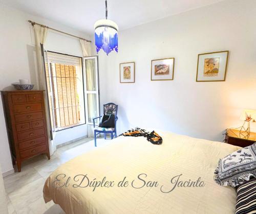 una camera da letto con un letto, una sedia e una finestra di El Dúplex de San Jacinto a Siviglia