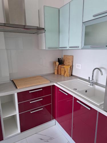 a kitchen with red cabinets and a sink at Apartman SIX in Brela