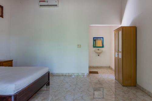 a bedroom with a bed and a cabinet in it at Hotel O Gunung Mas Homestay in Pemuteran
