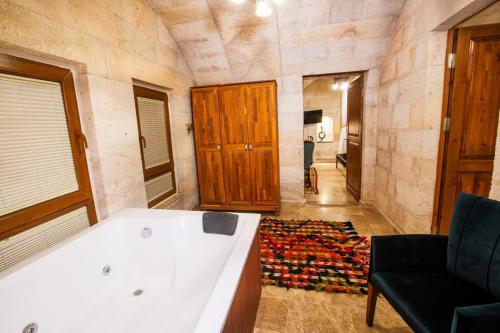 a bathroom with a tub and a chair and a room at Caldera Cave Hotel in Uchisar