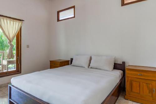 a bedroom with a white bed and a window at Hotel O Gunung Mas Homestay in Pemuteran
