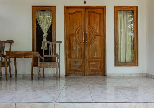 an empty room with a wooden door and a chair at Hotel O Gunung Mas Homestay in Pemuteran