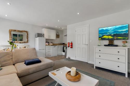 Una sala de estar con un sofá y una cocina. en The Snug - Brixham, en Brixham